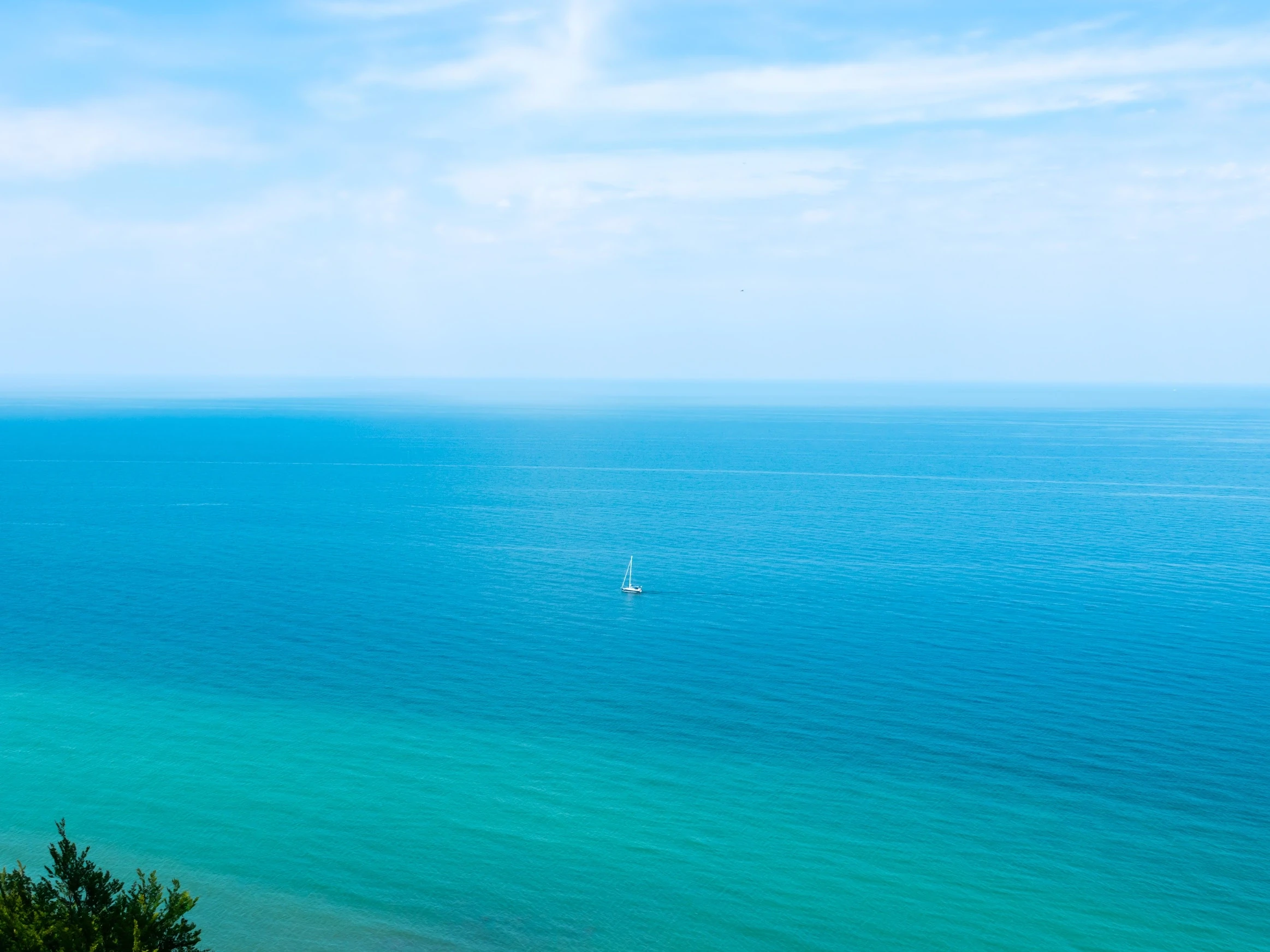 Blue sea meeting the horizon beneath a cloud-streaked sky