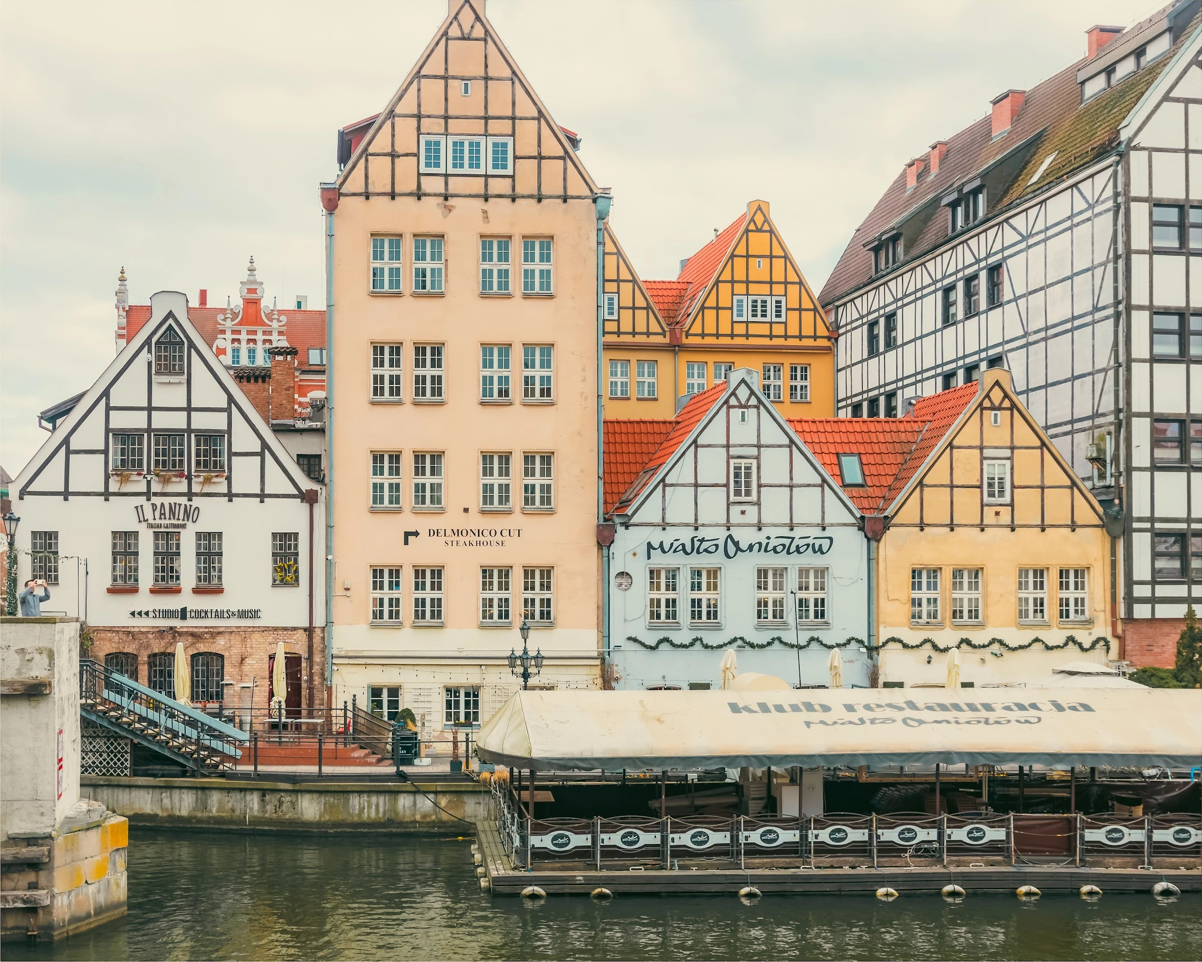 Gabled waterfront houses and restaurant terraces beside the water in Gdańsk.